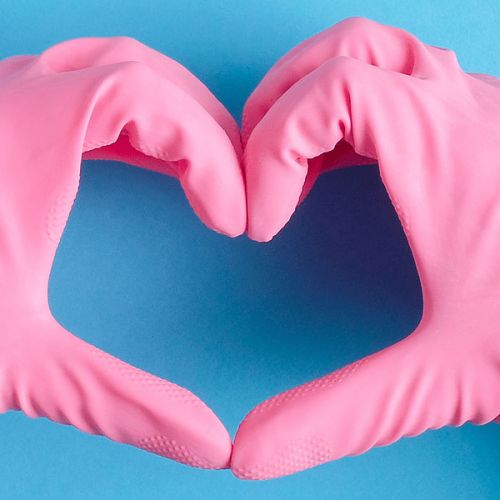 Hände in Reinigungshandschuhe, die ein Herz formen